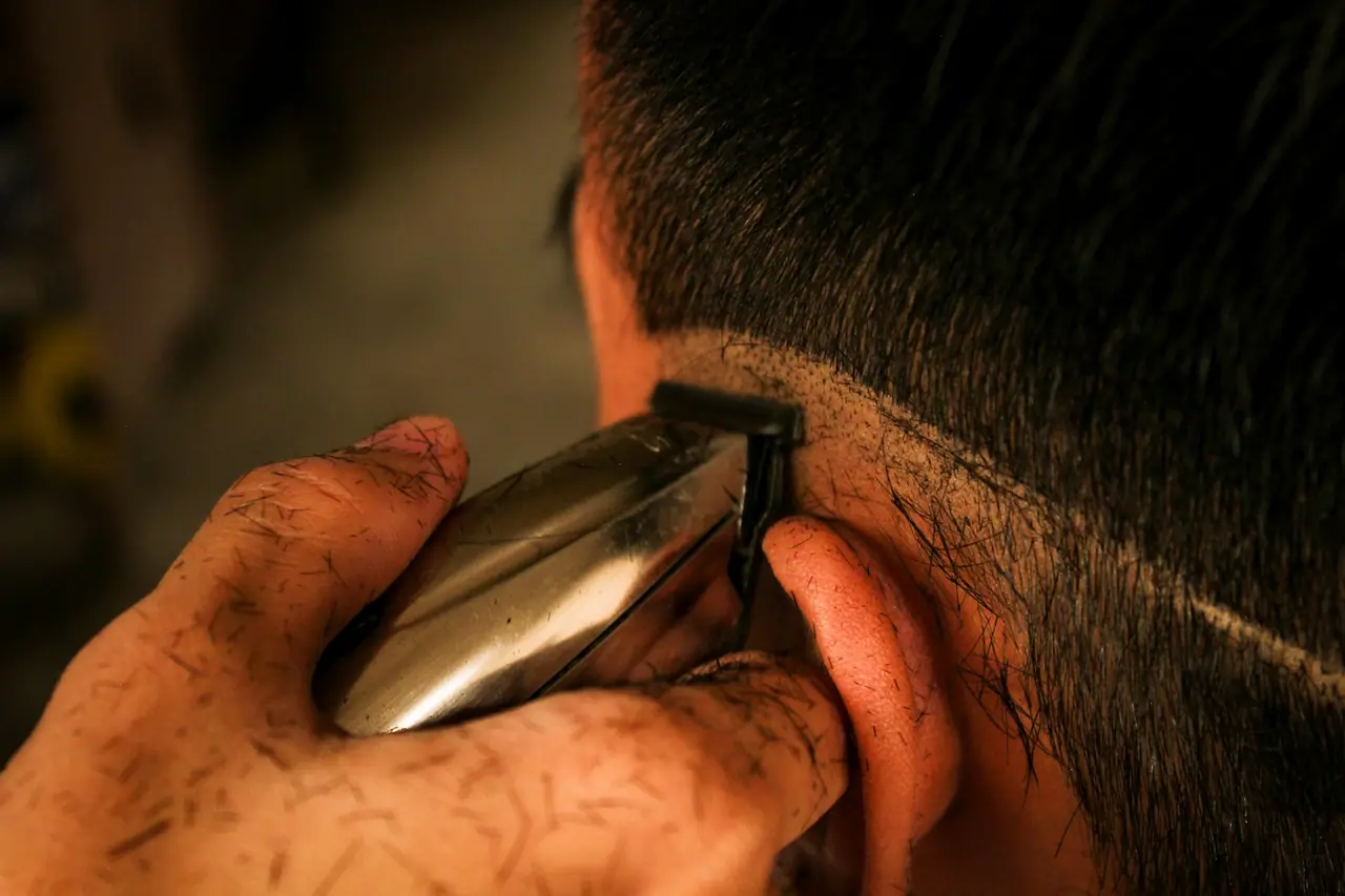 A barber's trimmer cutting a clean line behind the ear